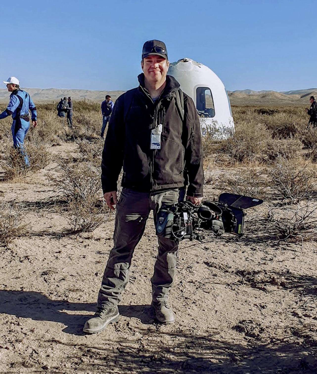 Kevin Curran with his camera beside the New Shepard capsule after the NS-19 landing in West Texas
