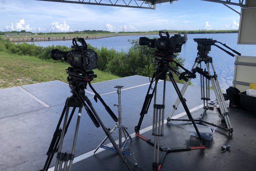 Broadcast cameras on a riser beside the water at Kennedy Space Center
