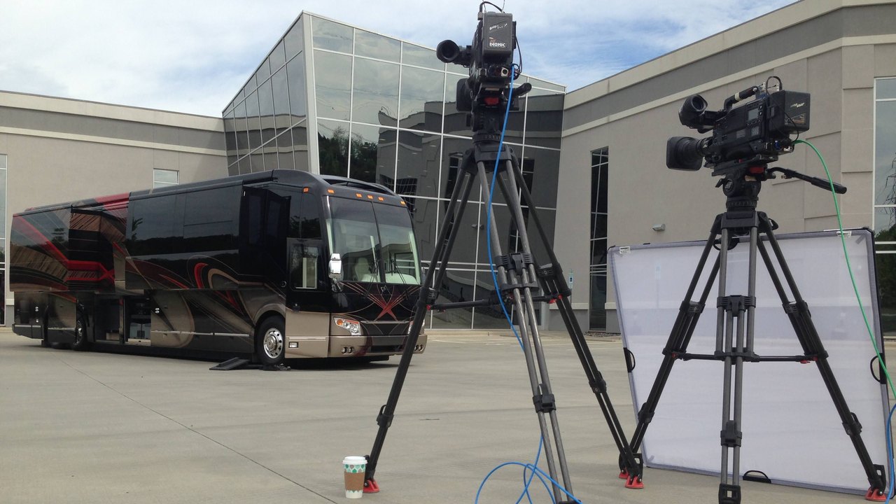 Two cameras on tripods set up to film a luxury motorcoach